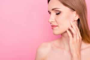 Profile of a woman touching her face to show that she is considering facial implants.