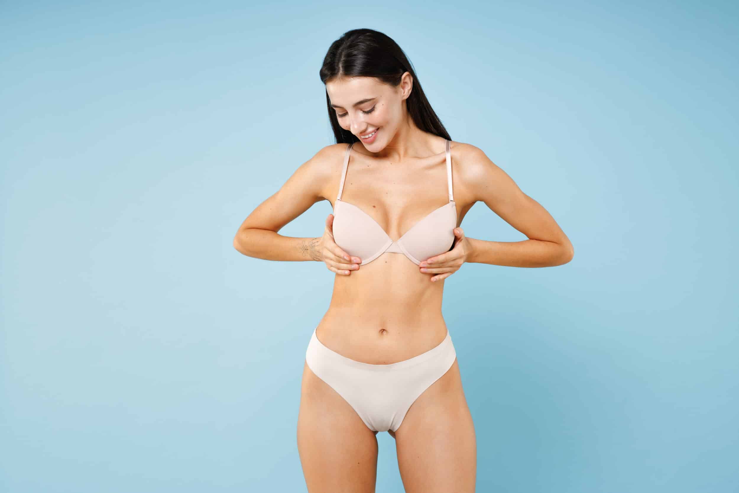 Toned woman clutching her breasts, in need of a fat-transfer breast reconstruction