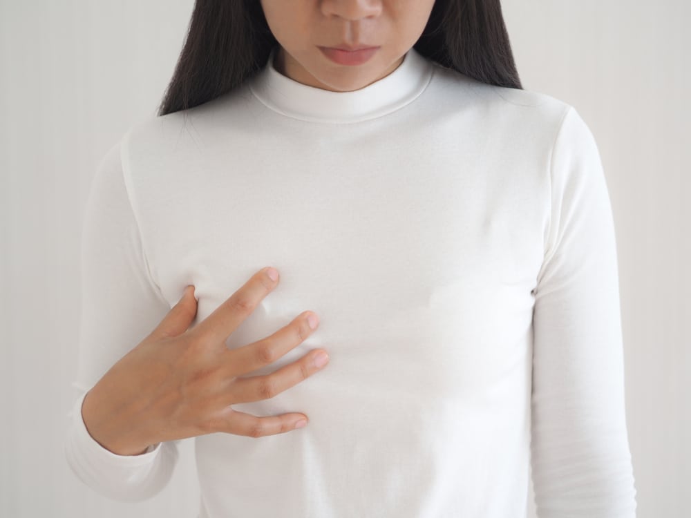 Woman touching her breast sadly, in need of a breast reconstruction.