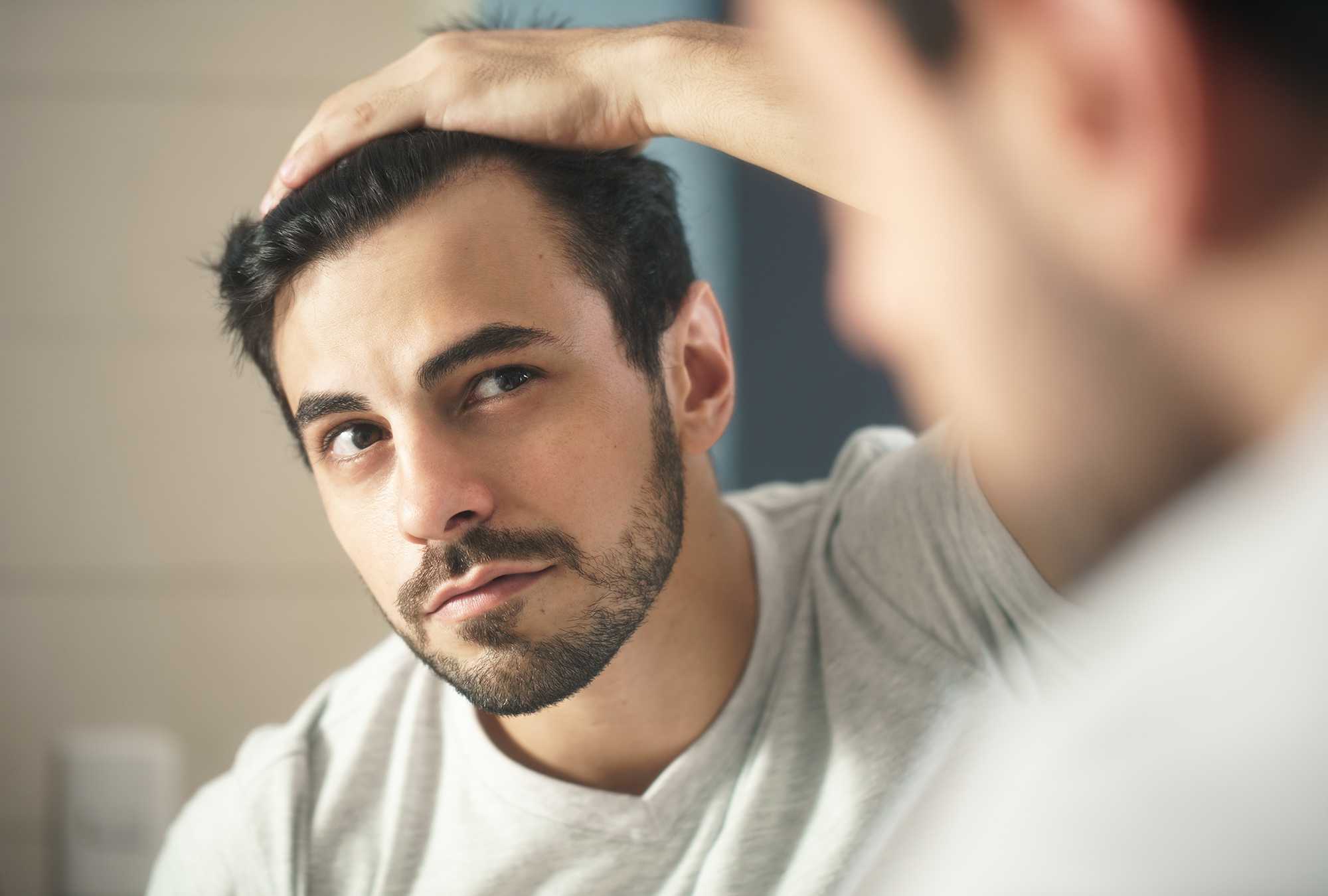 Man checks hair in mirror