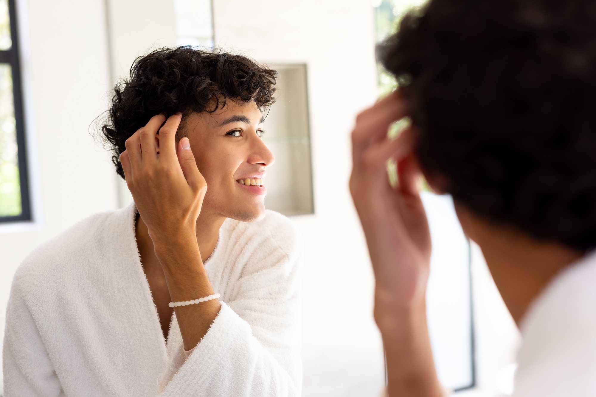 Young man styling curly hair.